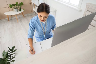 Klinikteki resepsiyonda çalışan Asyalı kadın stajyer.