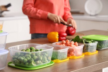 Sebzeli plastik kaplar ahşap masada donmak için kadınlar da arka planda.