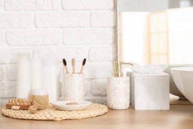 Banyodaki beyaz tuğla duvarın yanında banyo malzemeleri.