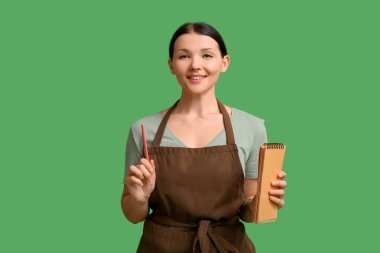 Yeşil arka planda defter ve kalemle güzel bir garson kız.