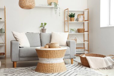 Yastıklı rahat kanepe, hasır sehpa, puf ve ekoseli sepet.