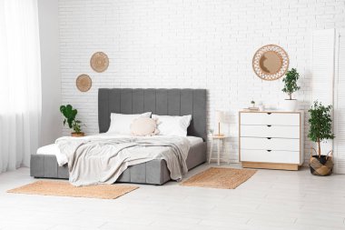 Büyük yataklı, çekmeceli ve bitkilerle dolu modern bir oda.