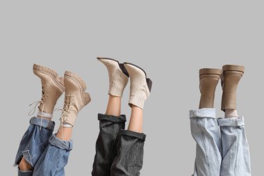 Gri arka planda farklı çizmeleri olan kadın bacaklar.