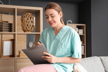 Genç bir tıp öğrencisi panoya yazı yazıyor ve evdeki kanepede oturuyor.