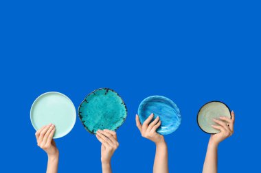 Mavi arkaplanda boş tabakları tutan eller