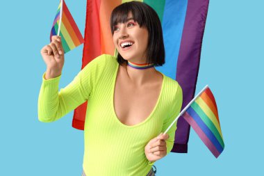 Mavi arka planda LGBT bayrakları olan gökkuşağı boyunduruklu güzel genç bir kadın.