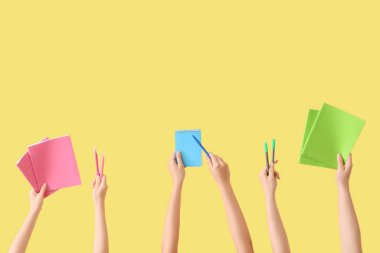 Okul gereçleri ve sarı arka planda defterleri olan kadın eller.