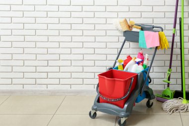 Beyaz tuğla duvarın yanında temizlik malzemeleri olan bir tramvay.