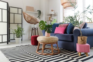 Mavi kanepeli, puflu ve bitkilerli şık bir oturma odası.