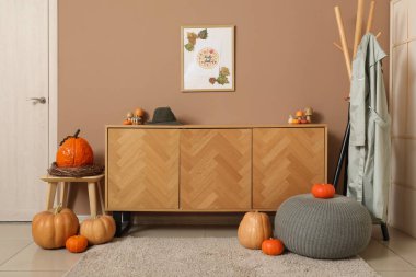 Koridorun içinde sonbahar dekoru, klozet ve askılık var.