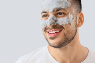 Yüzünde kozmetik balon maskesi olan yakışıklı, genç ve mutlu bir adam.