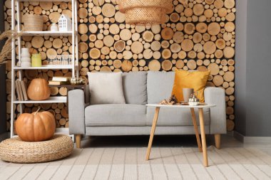 Sonbahar dekoru, kanepesi ve raf ünitesi olan oturma odasının içinde.