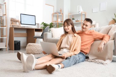 Evde dizüstü bilgisayar kullanan genç bir çift.
