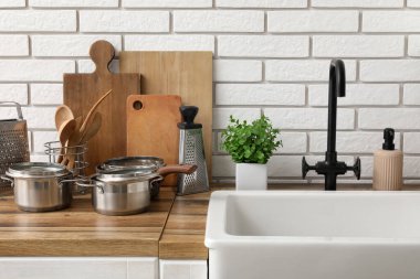 Temiz tabaklar ve mutfak aletleri lavabonun yanındaki ahşap tezgahta.