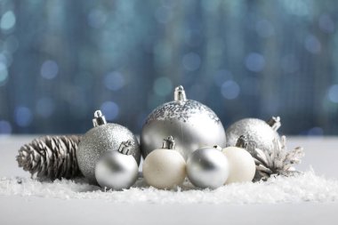 Bulanık ışıklara karşı masada kar ve koni ile Noel topları