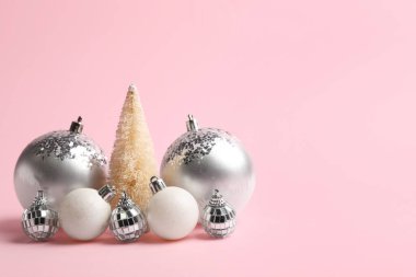 Pembe arka planda Noel topları ve ağaç