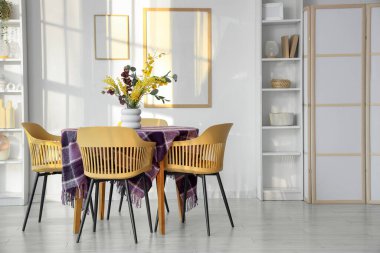 Yemek odasının içinde güzel çiçekler ve şık mor kumaşlar var.