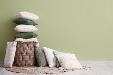 Yeşil duvarın yanındaki yastıklı sepet.