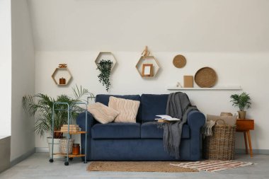 Mavi kanepe ve çiçeklerle aydınlık oturma odasının içinde.