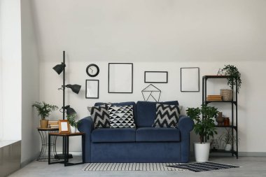 Mavi rahat kanepe, raf ünitesi ve oturma odasının iç tarafındaki çiçekleri.