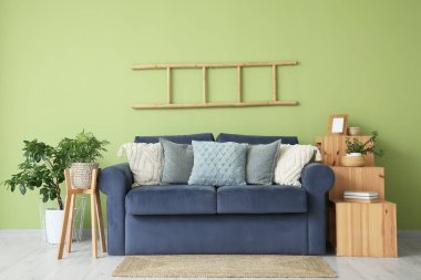 Oturma odasının içinde mavi kanepe, merdiven ve raf ünitesi var.