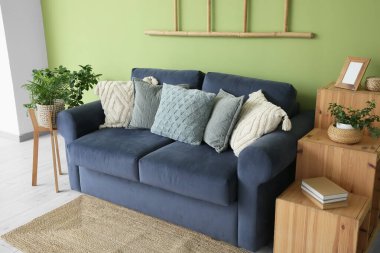 Oturma odasının içinde mavi kanepe, merdiven ve raf ünitesi var.