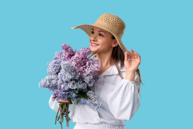 Beautiful young woman with bouquet of blooming lilac flowers on blue background