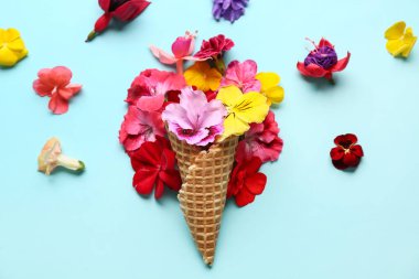 Mavi arka planda farklı güzel, yenilebilir çiçekli waffle külahı.