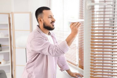 Ofiste pencerenin yanında kağıt uçağı olan genç bir adam.