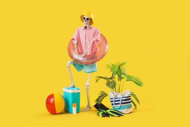 Sarı arka planda plaj aksesuarları olan insan iskeleti.