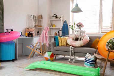 Oturma odasındaki kanepede plaj aksesuarlarıyla insan iskeleti.