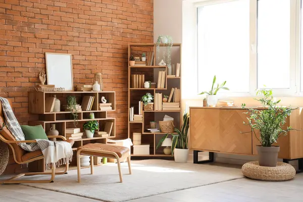 Koltuk, çekmece sandığı, kitap ve çiçeklerle dolu raf üniteleri ev kütüphanesinin içinde.