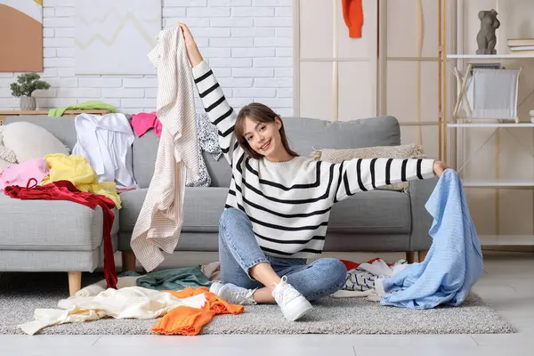Dağınık giysileri olan güzel, genç, mutlu bir kadın dağınık bir odada yerde oturuyor.