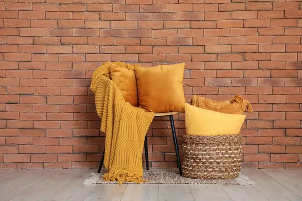 Koltuk, ekoseli, dekoratif yastıklı ve sepetli oda duvarının yanında.