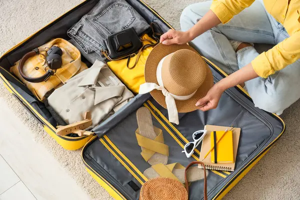 Genç bir kadın seyahat aksesuarlarını bavula yerleştiriyor.