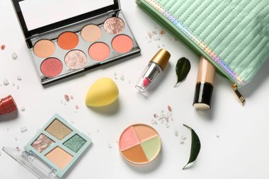 Beyaz arkaplanda makyaj ürünleri bulunan şık kozmetik çanta