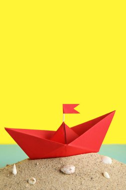 Kum ve deniz kabuklarının renginde kırmızı origami teknesi