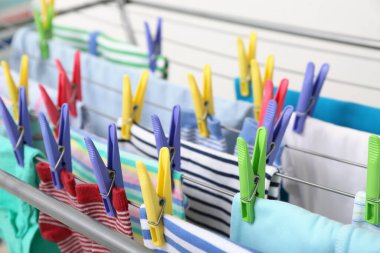 Temiz bebek kıyafetleri kurutucuda asılı, yakın plan.