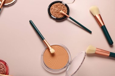 Pembe arka planda makyaj fırçaları ve yüz pudraları