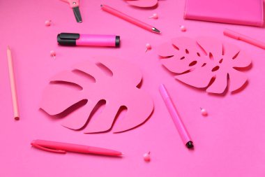 Pembe arka planda farklı kırtasiye malzemesi ve kağıt palmiye yaprakları olan kompozisyon