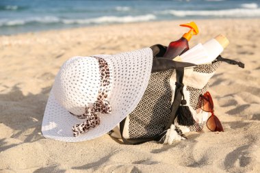 İçinde güneş kremi, şapka ve güneş gözlüğü olan bir çanta.