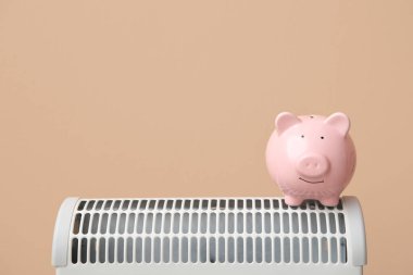 Evdeki bej duvarın yanındaki elektrikli konteyner ısıtıcısının kumbarasında. Isıtma kaydetme kavramı