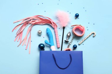 Seks oyuncakları ve mavi arka planda Noel dekoru olan bir alışveriş çantası.