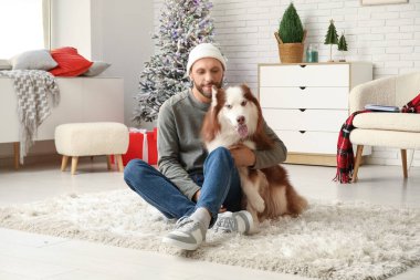 Evde sevimli köpekli yakışıklı bir genç adam.