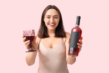Güzel genç kadın ile cam ve pembe bir arka plan üzerinde kırmızı şarap şişe