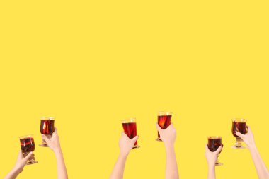 Sarı arka planda sıcak şarap kadehleriyle kadın elleri.