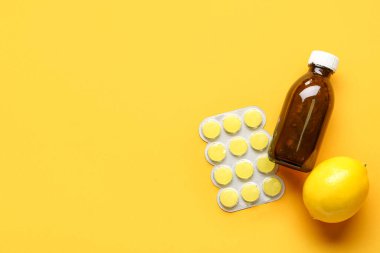 Boğaz ağrısı için ilaç, öksürük şurubu ve sarı arka planda limon.