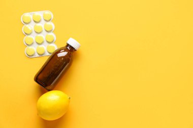 Boğaz ağrısı için ilaç, öksürük şurubu ve sarı arka planda limon.