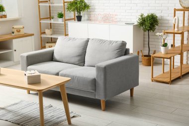 Gri rahat kanepesi ve çiçekleri olan bir oturma odası.