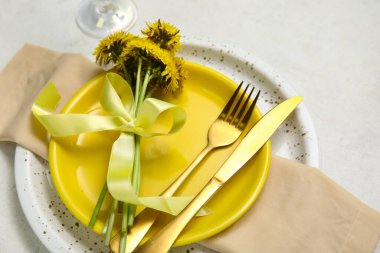 Altın çatal bıçak takımı ve beyaz arka planda karahindiba çiçekleri olan güzel bir masa.